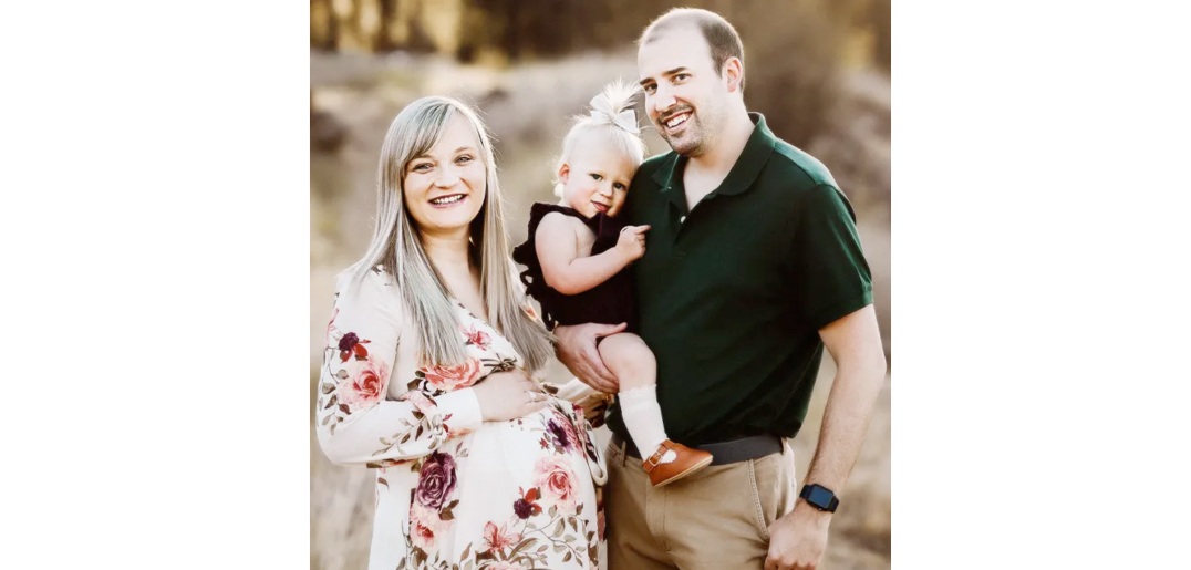 Mirranda is with her husband and daughter, surrounded by a field, and all three of them are smiling
