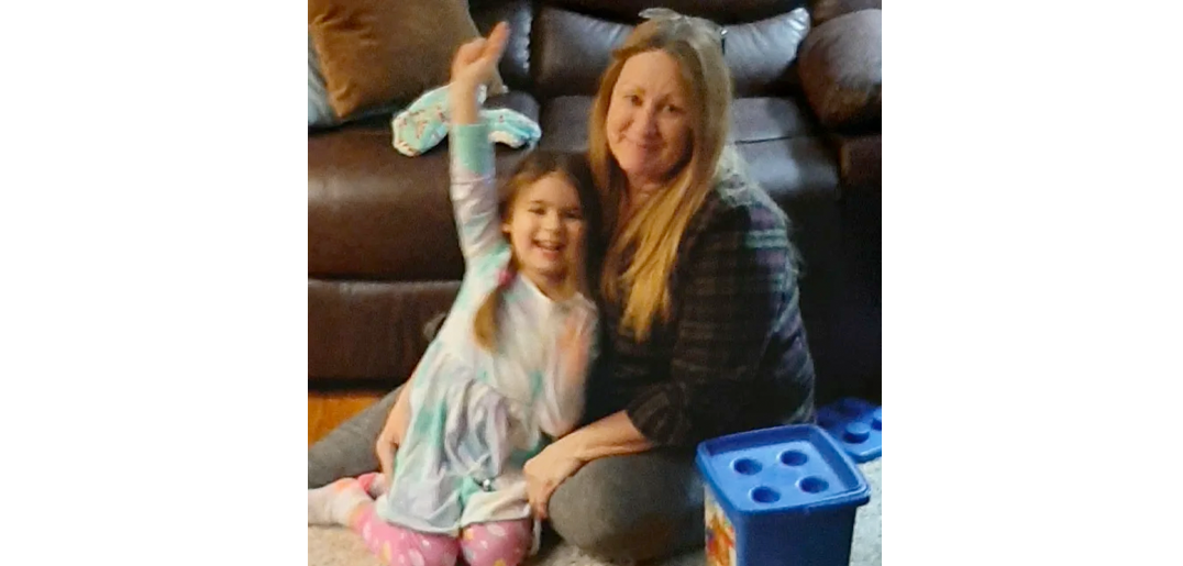 Kelly sitting on the living room floor with her daughter, and both of them are smiling.