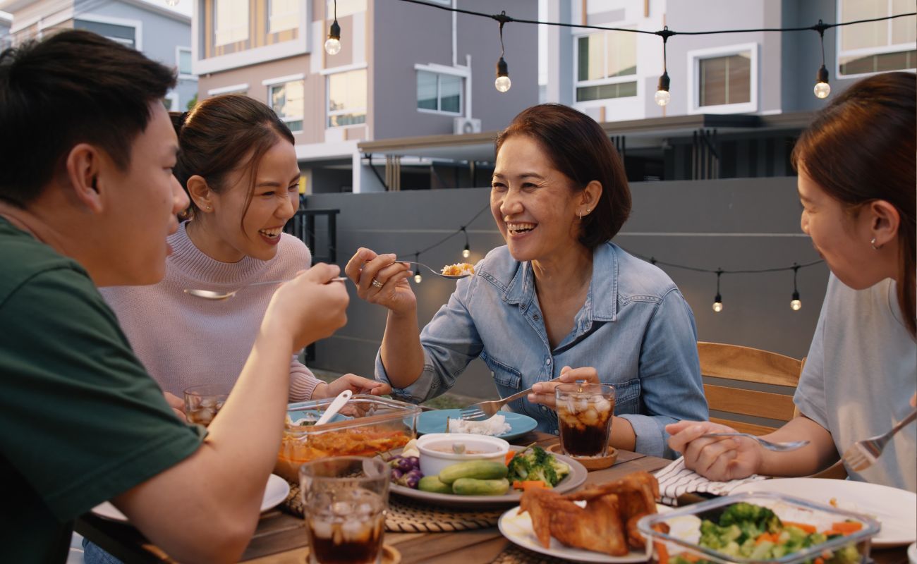 Two women and a man enjoying a meal outside and laughing
