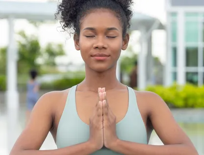 A woman closes her eyes and presses her palms together.