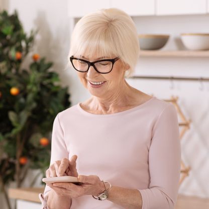 A woman is looking down at her smartphone and smiling.