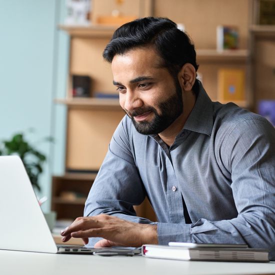 A man is working on his laptop and smiling.