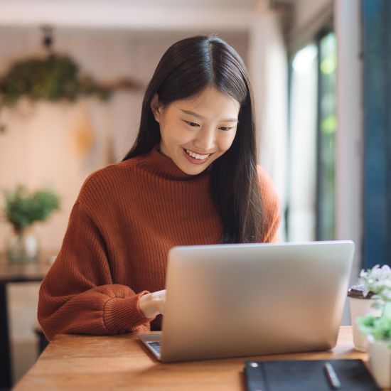 A woman is working on her laptop and smiling.
